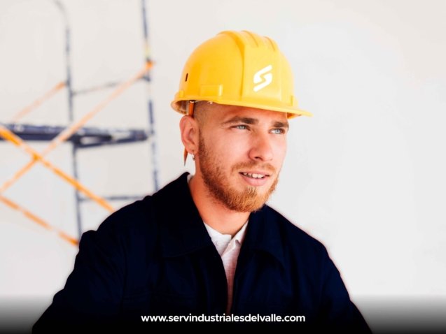 portrait-of-young-foreman-in-orange-work-clothes-and-yellow-hardhat-with-pencil-behind-ear-thoughtfully-looking-aside-with-scaffolding-on-background